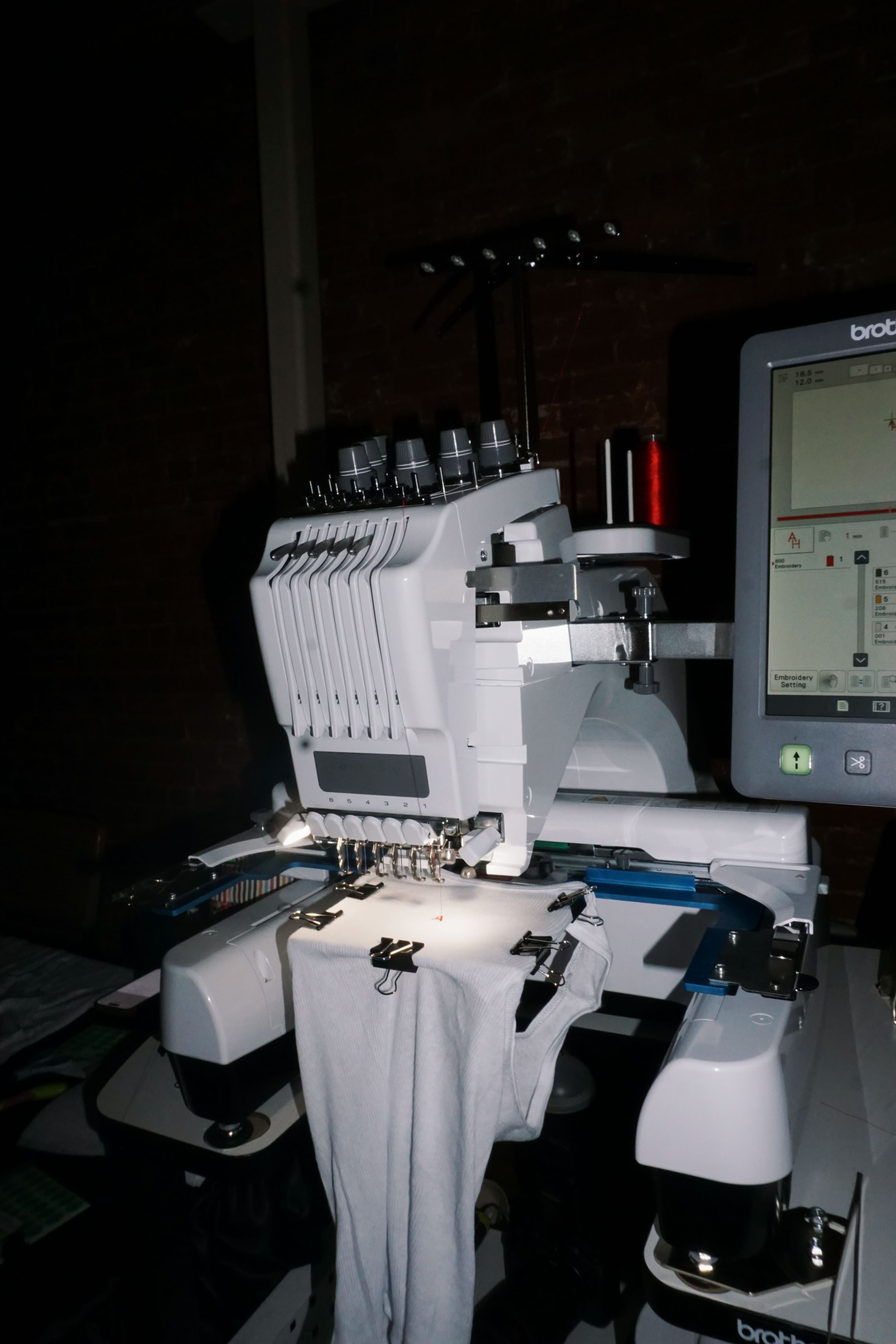 Embroidery machine mid-stitch, needle and thread working a custom Meya Made keepsake